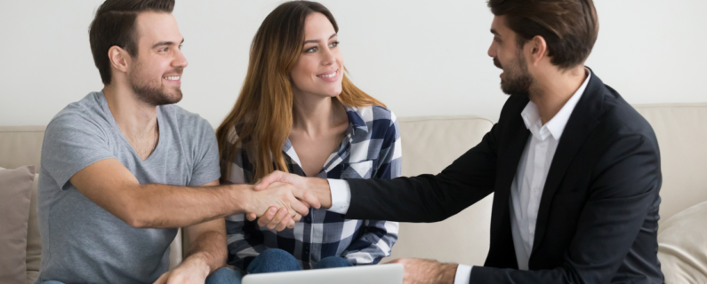 A couple shaking hands with a suited professional, suggesting a positive meeting or agreement