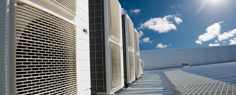 Property Management Rooftop HVAC units with metal grilles under a bright blue sky with scattered clouds